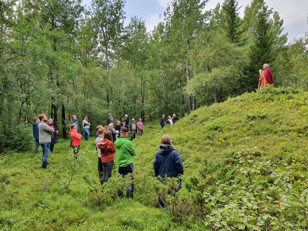 Person holder foredrag utendørs for mennesker om gamle vikinggraver. Foto