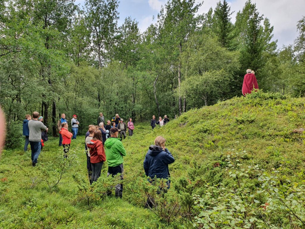 Person holder foredrag utendørs for mennesker om gamle vikinggraver. Foto