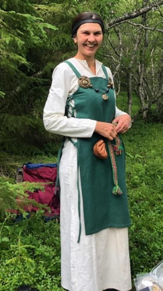 Smilende dame i vikingklær utendørs. Foto