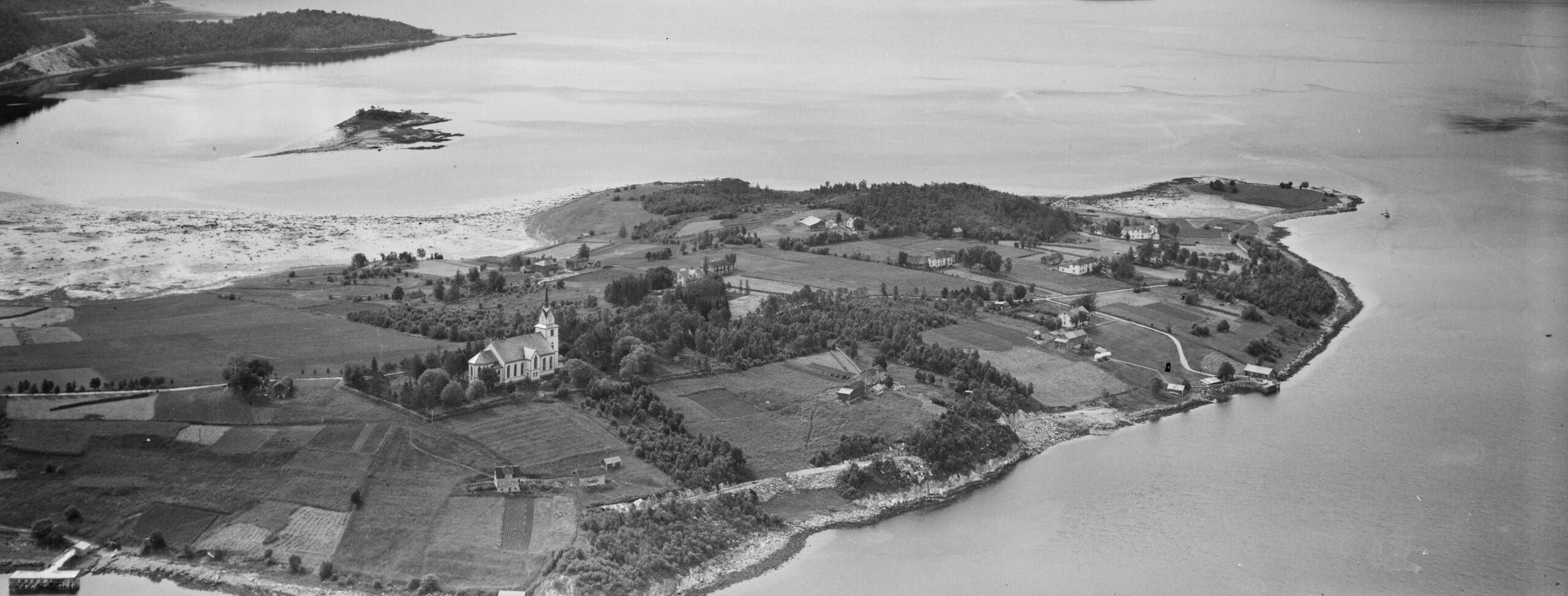 Foto fra 1950 av Skjerstad kirke sett fra luften. Foto
