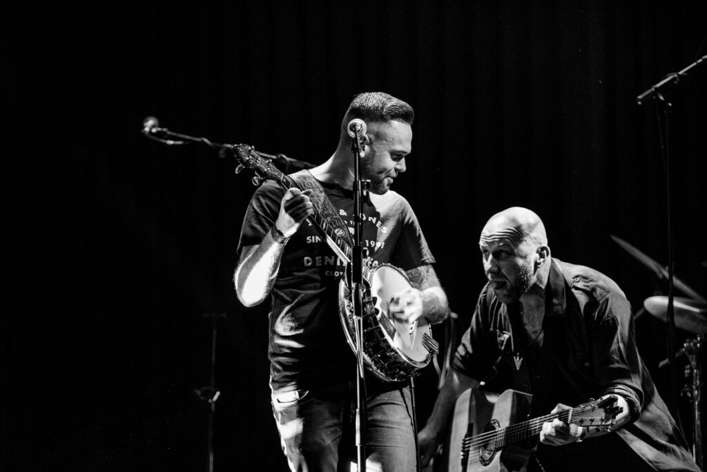 Bilde i svart-hvitt av to menn som spiller på banjo og gitar på en scene. Foto. 